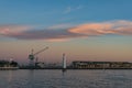 Wharf with hoisting crane and lighthouse at dusk