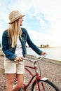 What a beautiful sight to see. a cheerful young woman wearing a hat and getting ready to ride her bicycle while looking