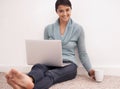 What better way to relax. Portrait of a young woman using her laptop and drinking a beverage.