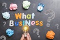 What business to start, question on blackboard with colourful letters, crumpled paper and light bulb