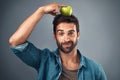 Is this what they call a balanced diet. Studio shot of a handsome young man balancing an apple on his head against a Royalty Free Stock Photo