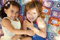 What childhood is all about. High angle shot of two little girls lying down and playing on a blanket.