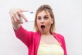 What?! Closeup portrait of unexpectedly attractive blogger woman in pink blouse standing, holding phone and making videocall with Royalty Free Stock Photo