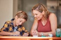 What did you learn at school today. a young woman helping her son with his homework at home. Royalty Free Stock Photo