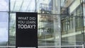 What did you learn today? on a city-center sign in front of a modern office building