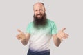 What do you need? Portrait of angry middle aged bald man with long beard in light green t-shirt standing, looking at camera with Royalty Free Stock Photo