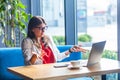 What do you need? Portrait of confused beautiful stylish brunette young woman in glasses sitting, looking at her laptop monitor on