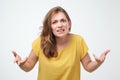 What do you want from me concept. portrait of unsatisfied angry emotional young woman in yellow t-shirt.