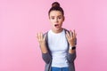 What do you want? Portrait of disgruntled teenage girl looking annoyed irritated with raised hands. isolated on pink background