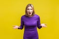 What do you want? Portrait of irritated angry woman standing with raised hands. isolated on yellow background