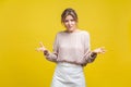 What do you want? Portrait of irritated young woman with fair hair in casual beige blouse, isolated on yellow background Royalty Free Stock Photo