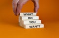 What do you want symbol. Wooden blocks with words `What do you want` on beautiful orange background. Businessman hand. Business