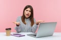 What do you want? Upset irritated woman office worker spreading hands sitting at workplace with laptop, looking at camera with Royalty Free Stock Photo