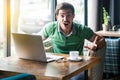 What do you want? Young angry businessman in green t-shirt sitting, looking and screaming at camera with aggressive crazy face