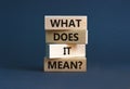 What does it mean symbol. Concept words `what does it mean` on wooden blocks. Beautiful grey background. Businessman hand.