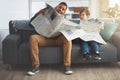 What does the paper say. a carefree little boy and his father reading the newspaper while being seated on the sofa at Royalty Free Stock Photo