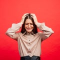 What is it. The female portrait isolated on red studio backgroud. The young emotional angry, scared woman looking at camera.The