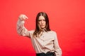 What is it. The female portrait isolated on red studio backgroud. The young emotional angry, scared woman looking at camera.The