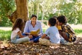 What fun activity should we do next. a teacher reading a book to her class in a park. Royalty Free Stock Photo