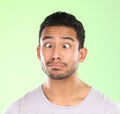 What a goofball. a handsome young man making a face against a green background in studio.