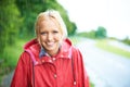 What a gorgeous smile. Gorgeous young blonde woman wearing a red raincoat in the rain outdoors on a country road. Royalty Free Stock Photo