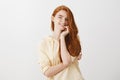 What great day for flirt and romance. Portrait of charming redhead female holding palm in cheek and smiling sensually Royalty Free Stock Photo