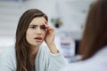 What happened last night. a confused looking young woman looking into a mirror with her hand touching her face at home Royalty Free Stock Photo