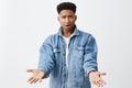 What the heck, man. Close up of young unhappy grumpy black-skinned american man in denim jacket with afro hairstyle