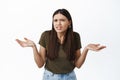 What I dont understand. Confused brunette woman staring puzzled at camera, shrugging and spread hands sideways clueless Royalty Free Stock Photo