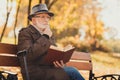 What lifestyle sense. Profile side photo of pensive old man rest relax in fall nature october trees park read book