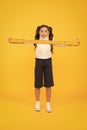 What a long ruler. Surprised little student holding rigid wooden ruler on yellow background. Small child taking Royalty Free Stock Photo