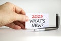 2023 what is new symbol. White card with words 2023 what is new. Businessman hand. Metallic pen. Beautiful white table white