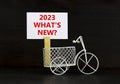 2023 what is new symbol. Wooden clothespin, white sheet of paper with words 2023 what is new. Miniature bicycle model. Beautiful Royalty Free Stock Photo