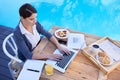 What a pleasant place to work. a young businesswoman working on her laptop by a swimming pool. Royalty Free Stock Photo