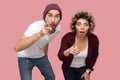 What? Portrait of shocked couple of friends in casual style standing and pointing finger to you with big eyes and opened mouth,