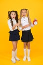 What is retro time. Surprised small children pointing at retro clock on yellow background. Little girls with open mouth