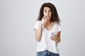 What shall I write back. Portrait of worried anxious attractive woman with curly hair in casual outfit holding