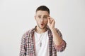 What shocking news you are telling. Portrait amazed office worker holding glasses while wearing it and standing over