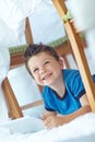 What should I use my tablet for next. A cute little boy sitting under a blanket fort while at home. Royalty Free Stock Photo