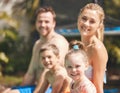 This is what summers are meant to look like. Cropped portrait of a young family of four sitting outside by the pool. Royalty Free Stock Photo