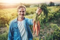 This is what time and effort looks like. Cropped portrait of a handsome young man holding a bunch of carrots and smiling Royalty Free Stock Photo