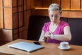 What time is it? Portrait of serious young bussineswoman with short hair in pink t-shirt is sitting in cafe, checking time on