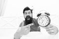 What time is it. Stressed man alarm clock. Sleepy man holding alarm clock in bed. Bearded man with alarm clock. Hipster