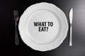 What to eat concept. Top view empty white plate on black background with question mark.