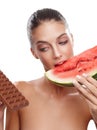 What she really wanted was the chocolate. Studio shot of a young woman eating a slice of watermelon while eying out a