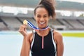 This is what winners get. Cropped portrait of an attractive young woman posing with her gold medal out on the track.