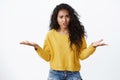 What wrong with you. Confused and intense pissed african-american woman in yellow sweater shrugging, spread hands