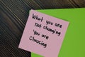 What you are not changing you are choosing write on sticky notes isolated on Wooden Table. Motivation concept Royalty Free Stock Photo