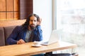 What you say? Interesting handsome young adult man freelancer in casual style sitting in cafe and talking with his friend in Royalty Free Stock Photo