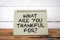 What Are You Thankful For. Green notepad on wooden texture table and white background Royalty Free Stock Photo